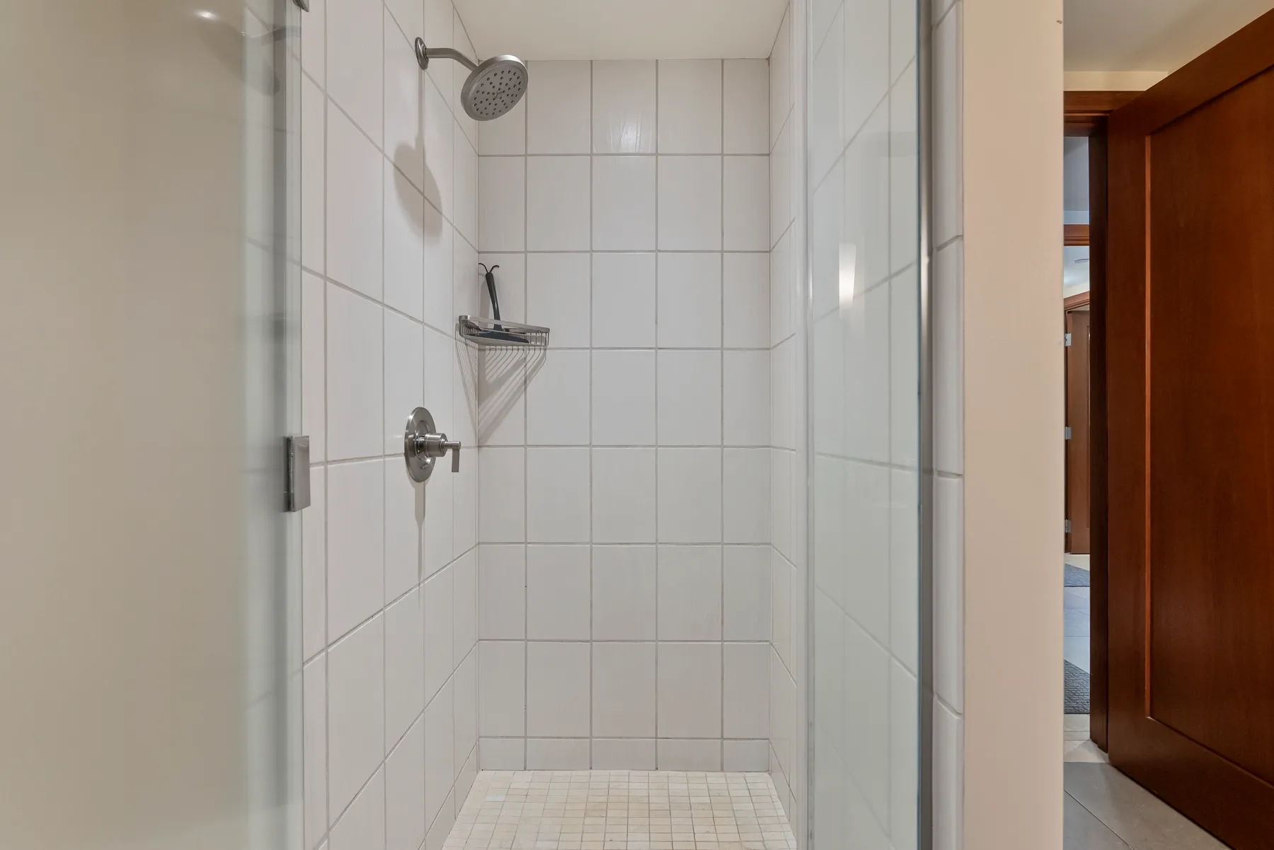 Una zona de ducha con azulejos, una ducha de pared y un control.