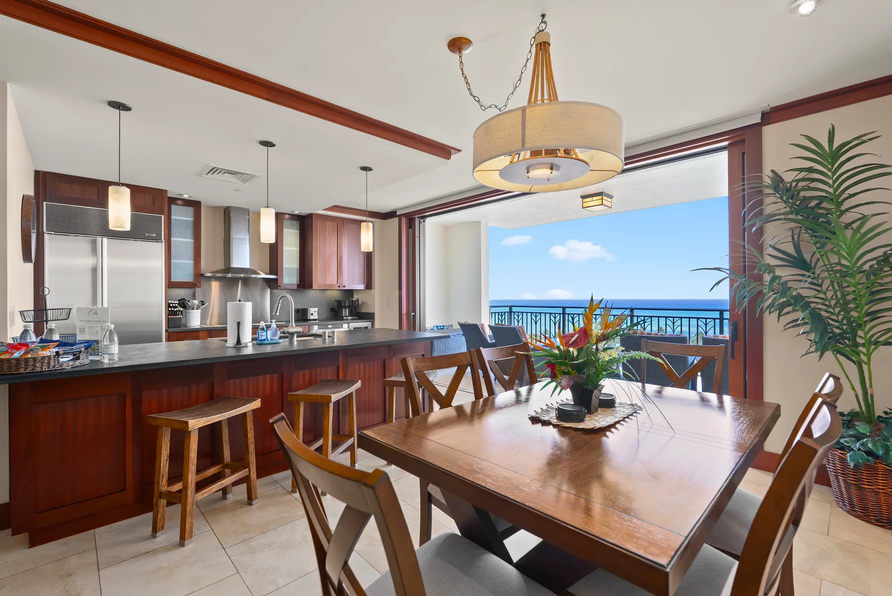Comedor con una mesa de madera junto a una cocina y una vista al mar.