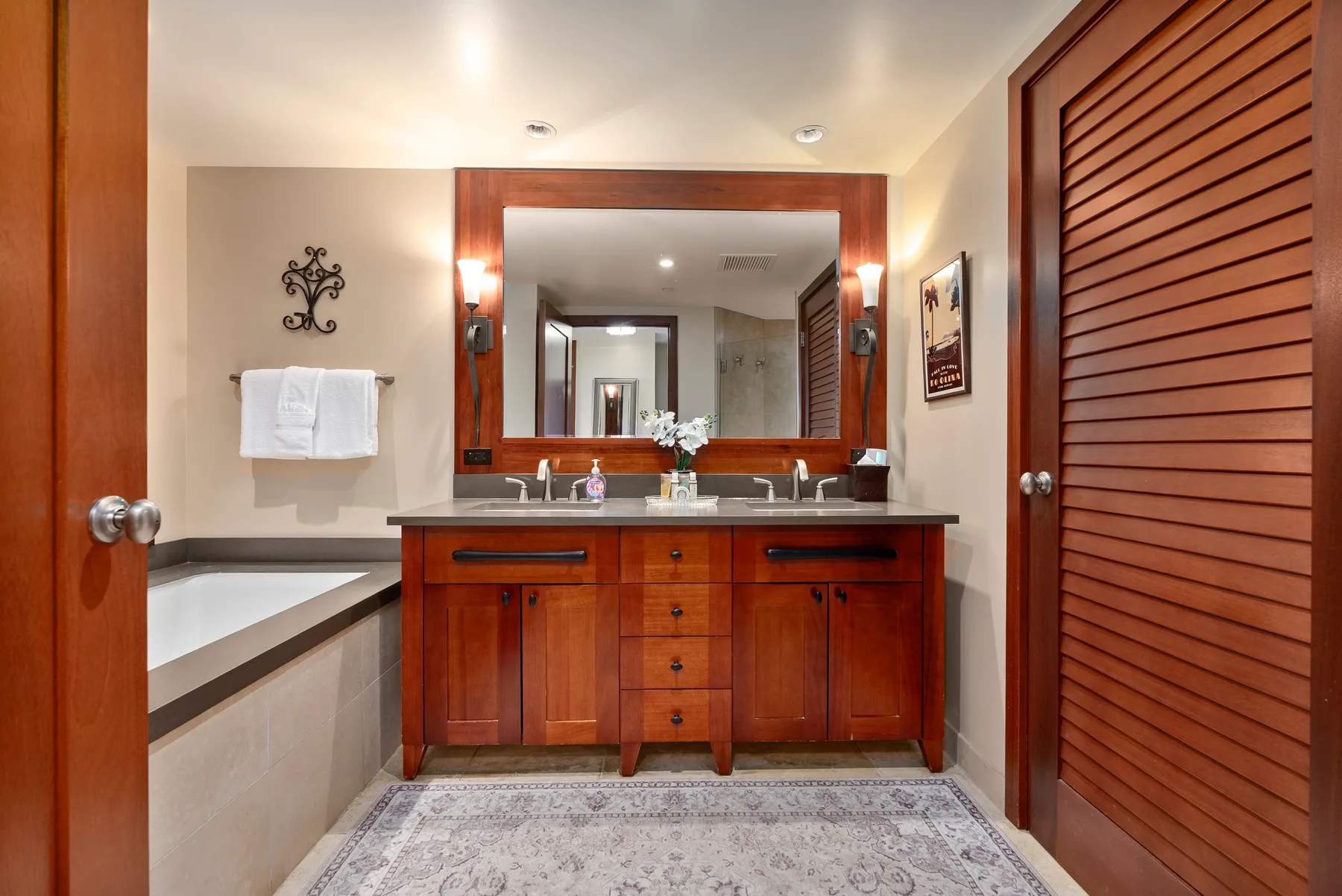 Un baño con un tocador de madera, un espejo grande y una bañera.