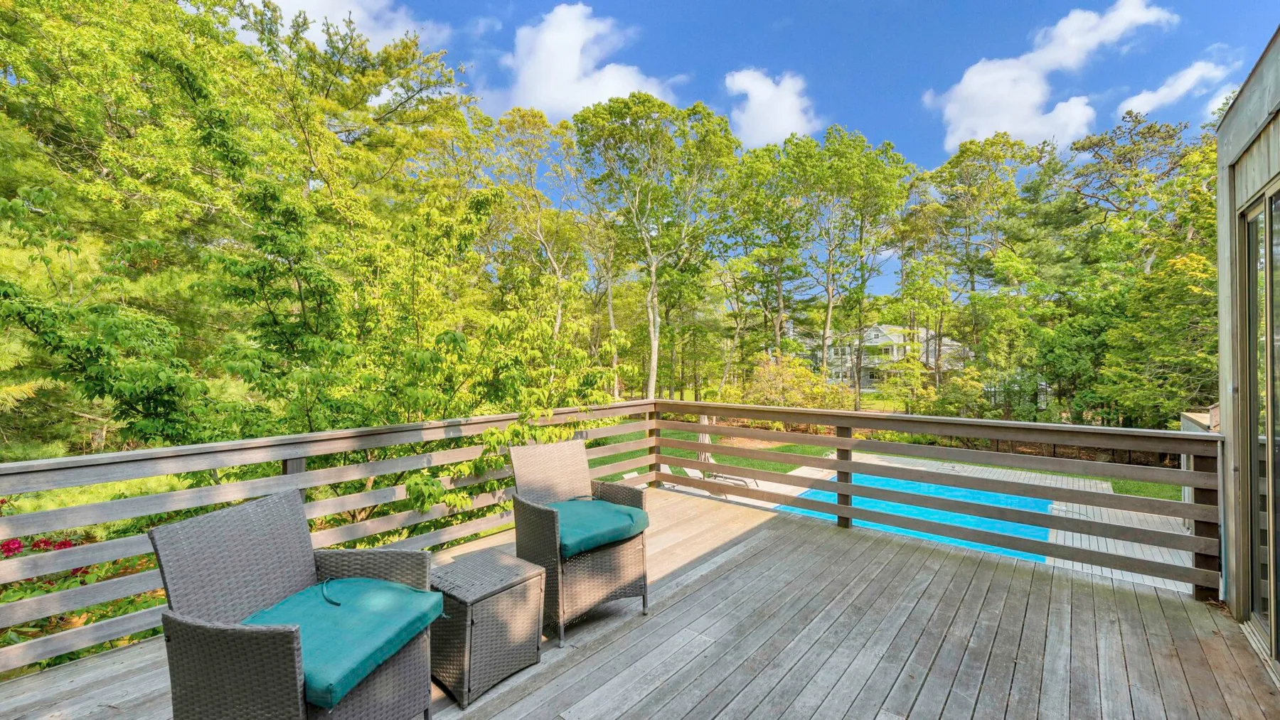 A wooden deck with outdoor seating overlooks a wooded landscape.