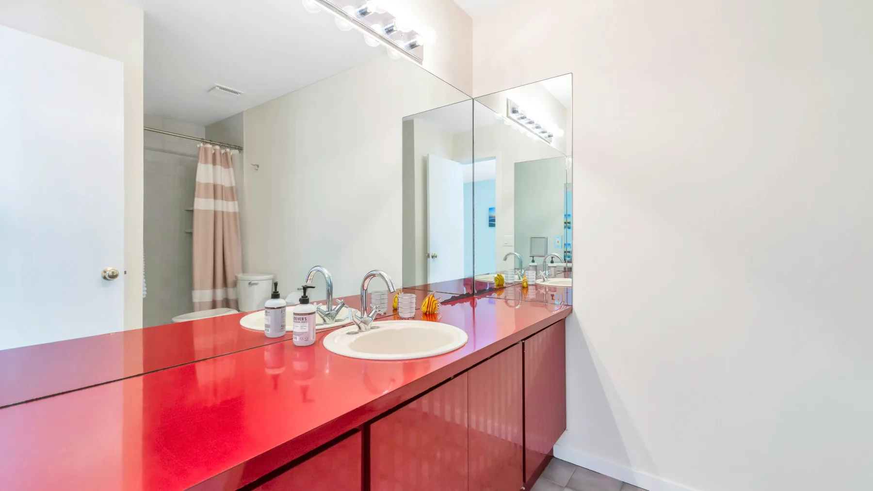 A bathroom vanity with a bright red countertop and a large mirror.