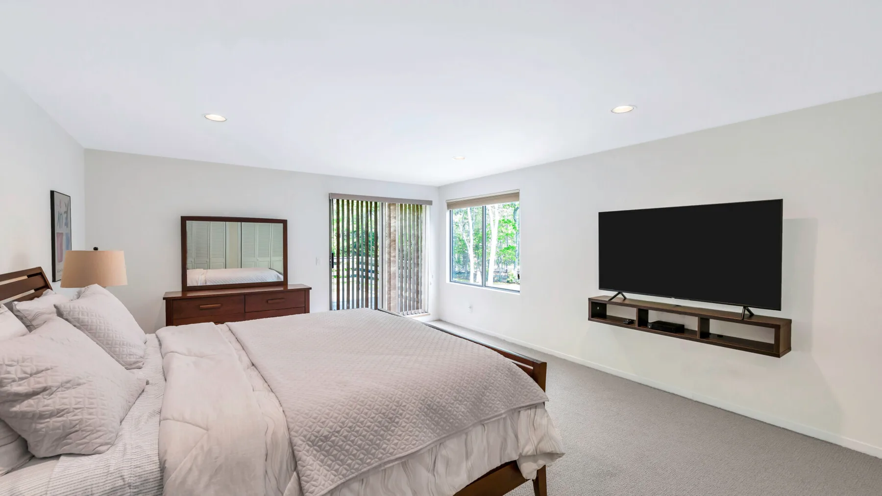 A bright bedroom with a bed and a wall-mounted television.