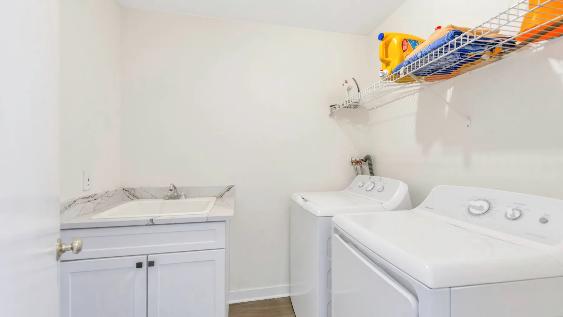 A laundry room with a washer, dryer, and wall-mounted storage rack.