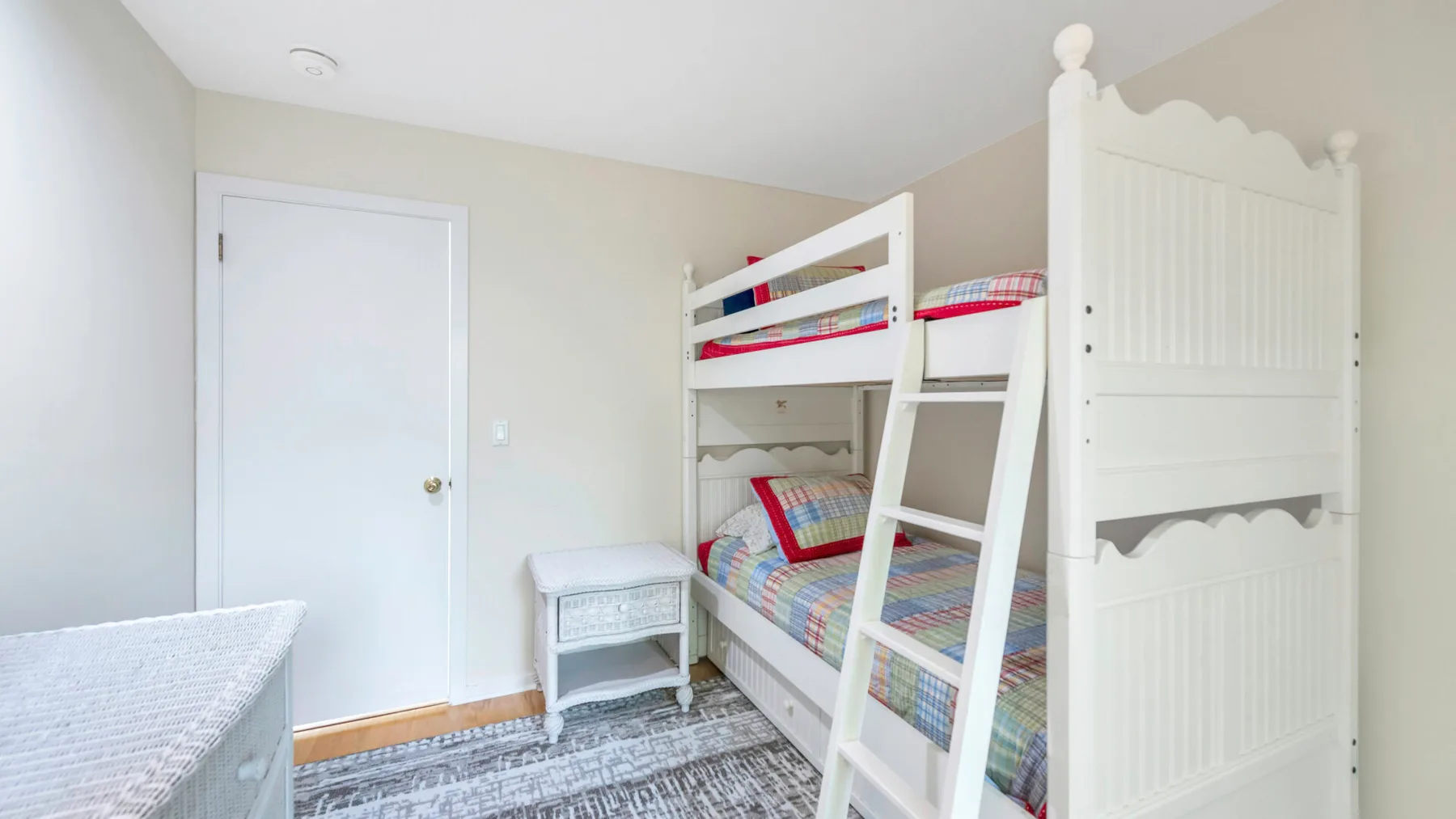 A bedroom with white bunk beds and colorful striped bedding.