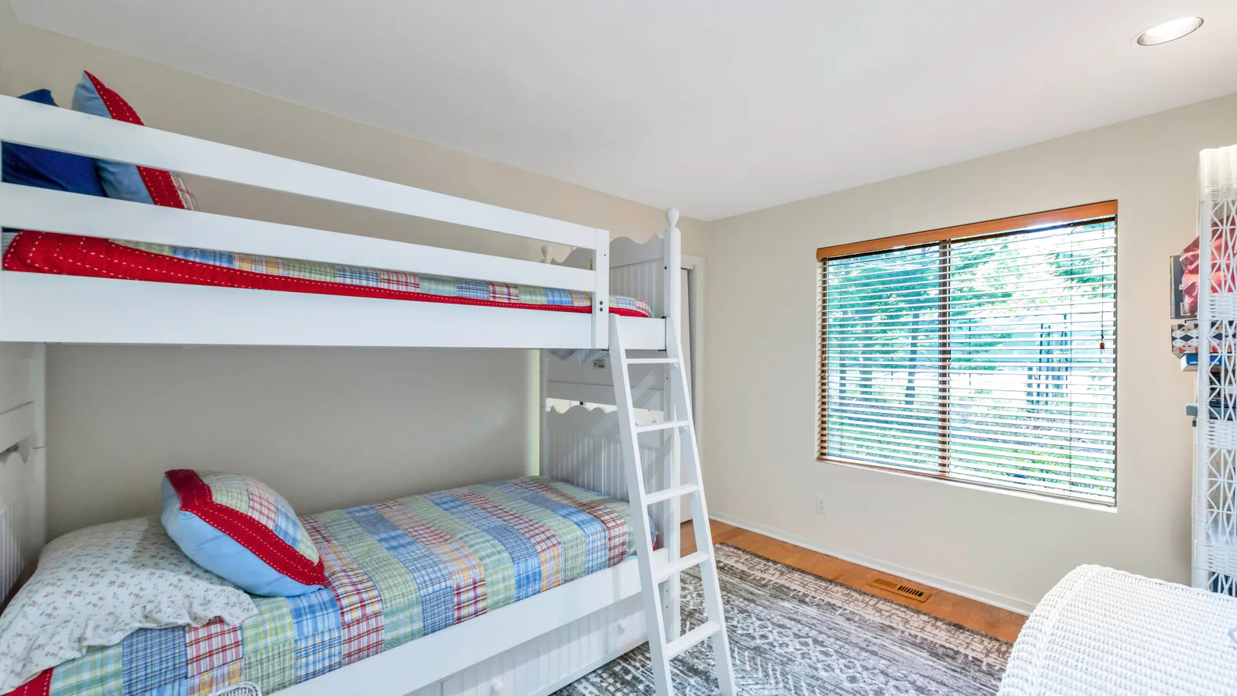 A bedroom with bunk beds, patterned bedding, and a window with blinds.