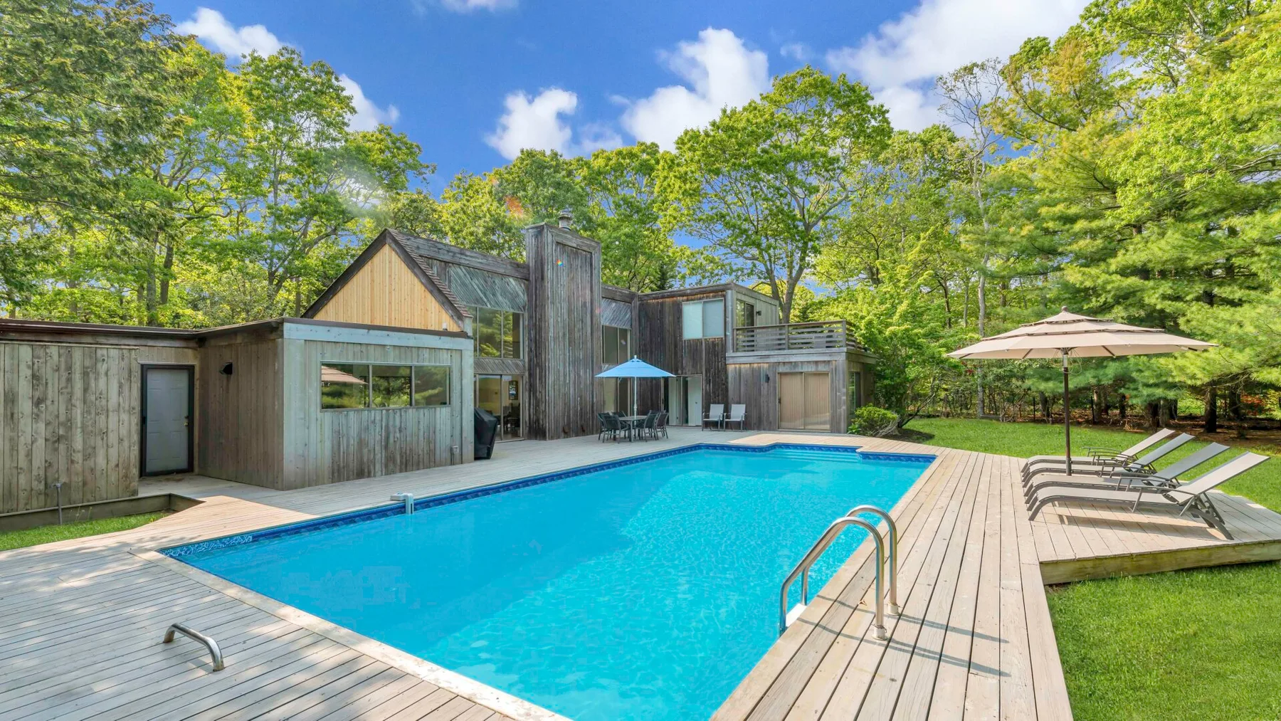 An outdoor swimming pool is surrounded by a wooden deck and trees.