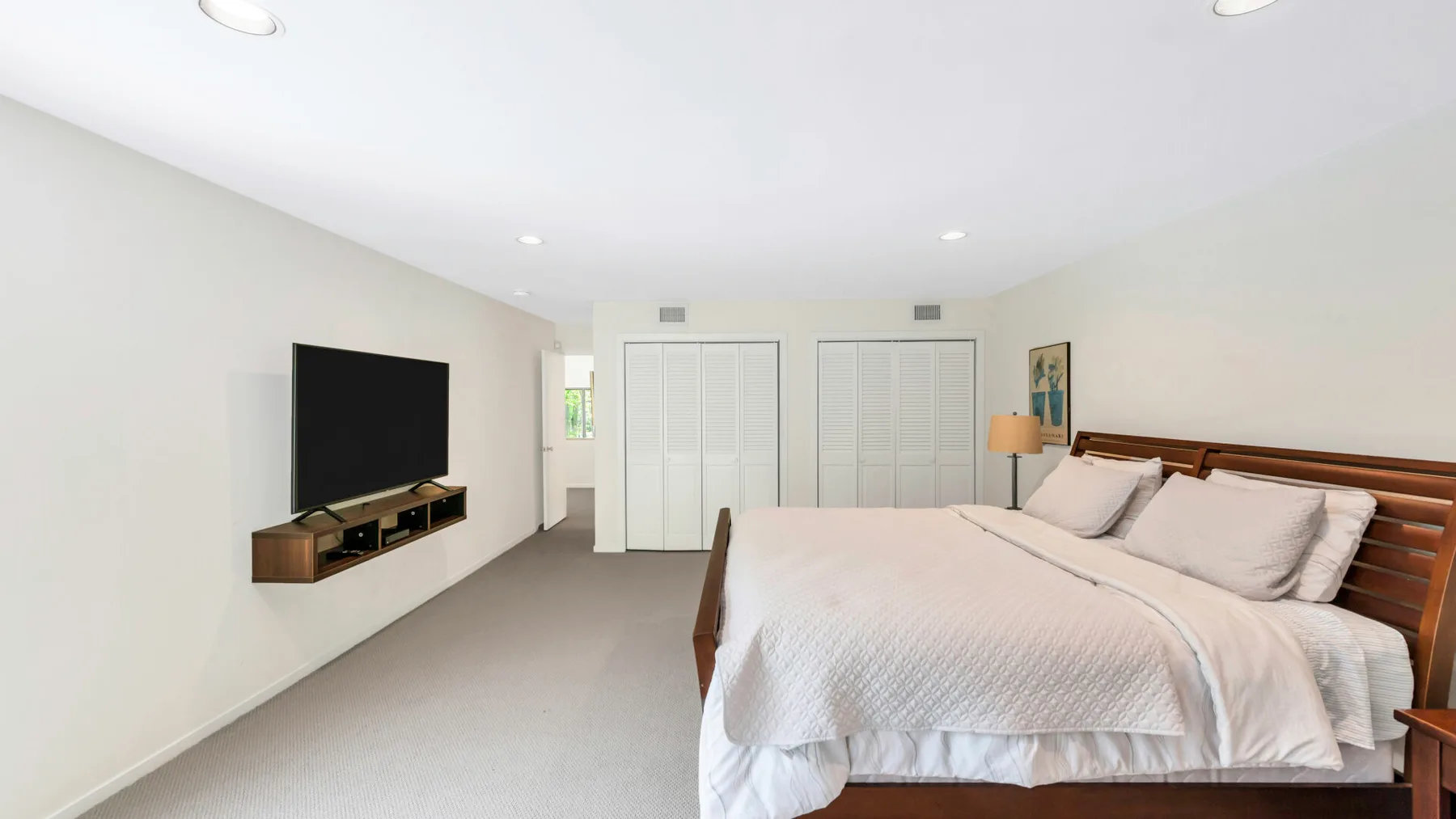 A bedroom with a large bed and a wall-mounted television.