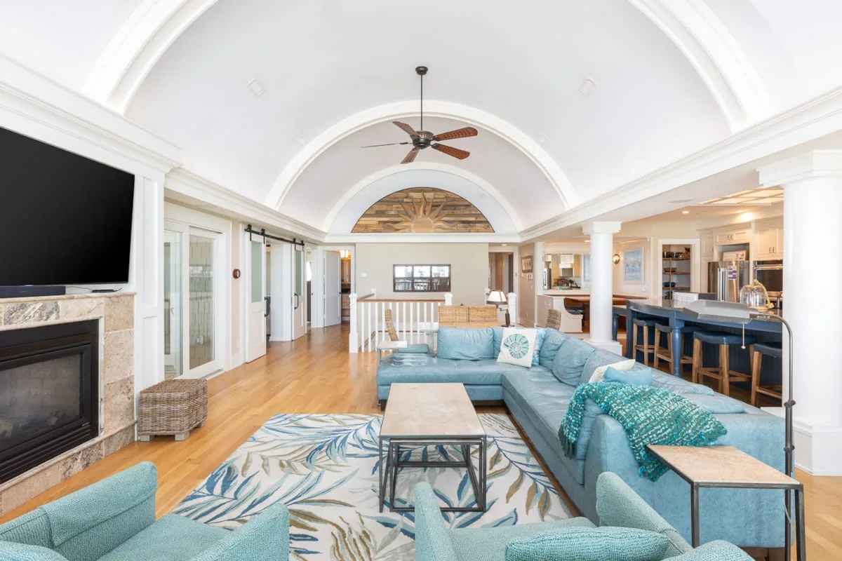 A bright living room with an L-shaped seating area and an open kitchen.