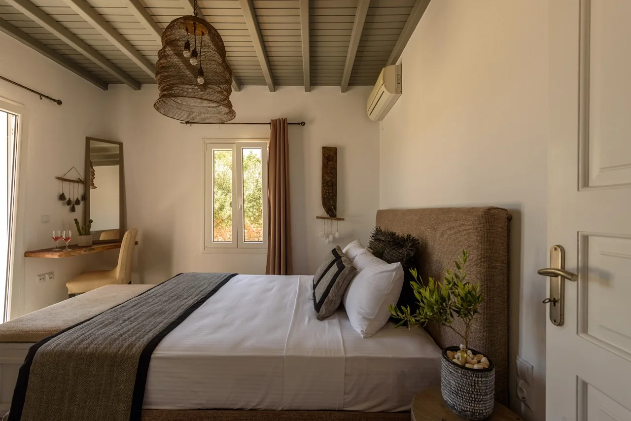 Un dormitorio con una cama tendida y una ventana enmarcada por cortinas.