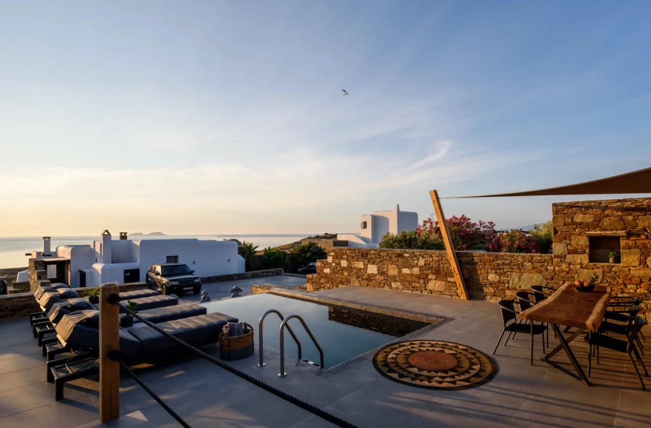 Una terraza en la azotea con piscina, asientos al aire libre y vistas al mar.