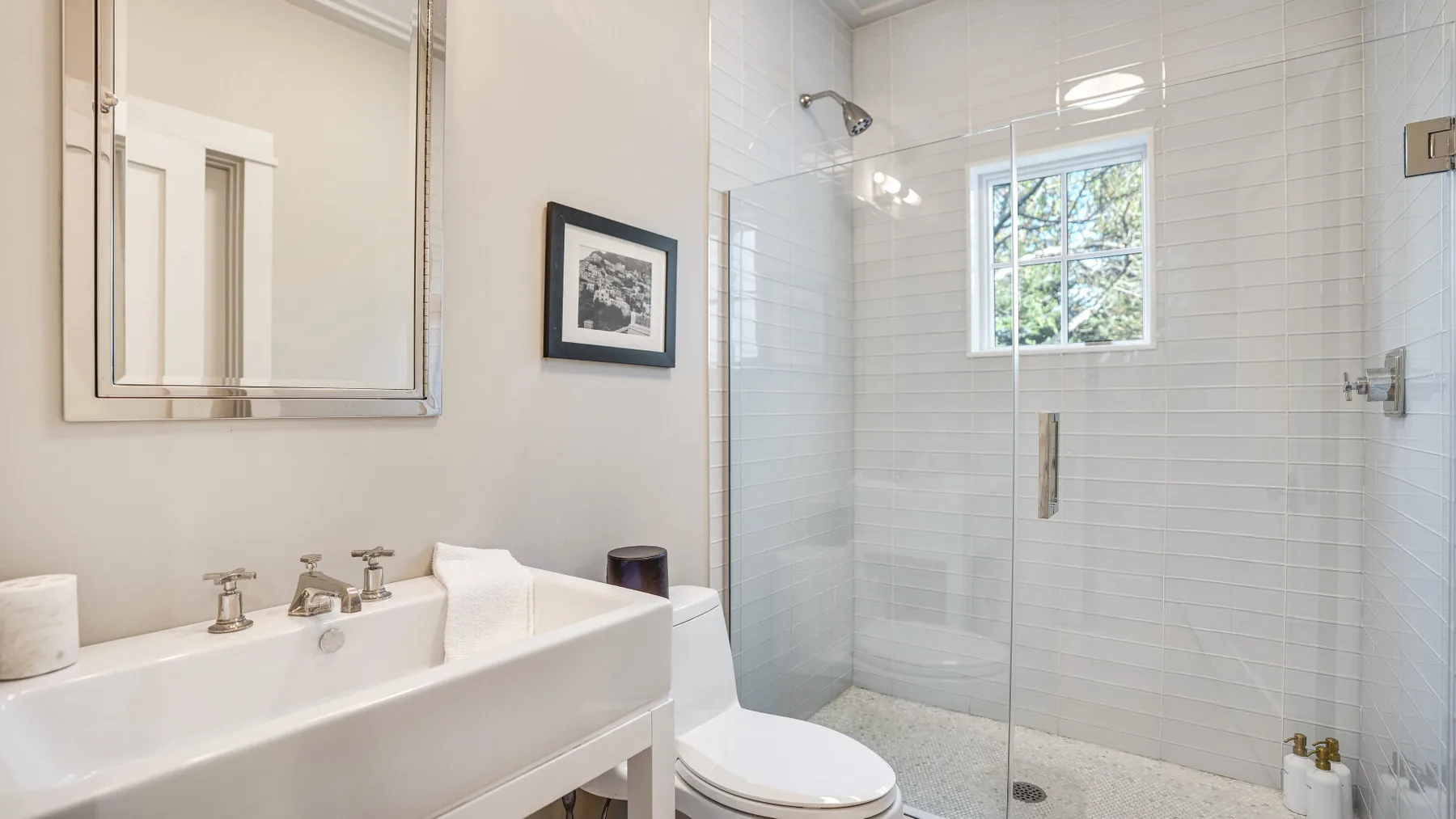Un baño luminoso con un lavabo y una ducha con mampara de vidrio.