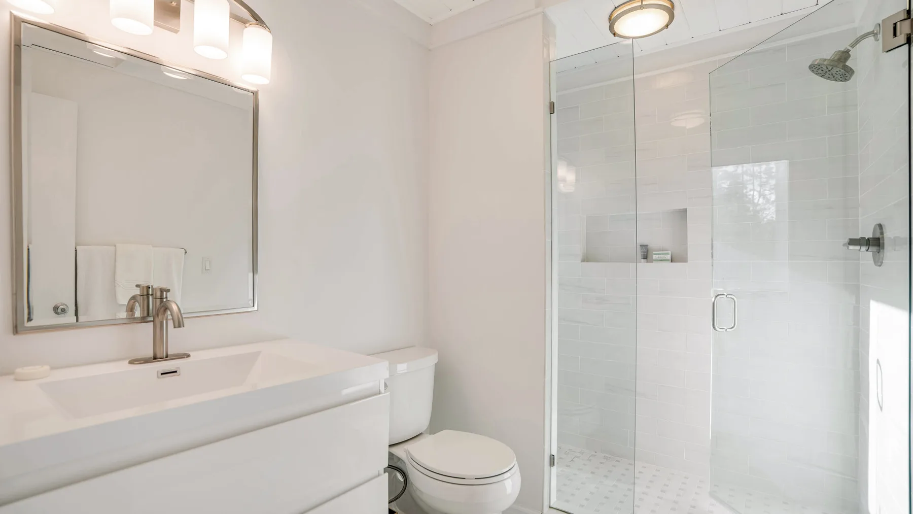 Un baño luminoso con lavabo y ducha con paneles de vidrio.
