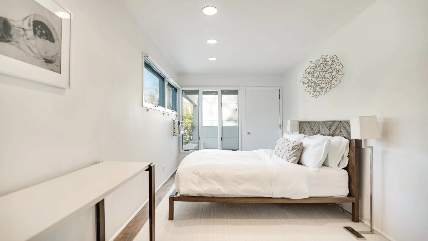 Un dormitorio luminoso con una cama junto a una fila de ventanas.