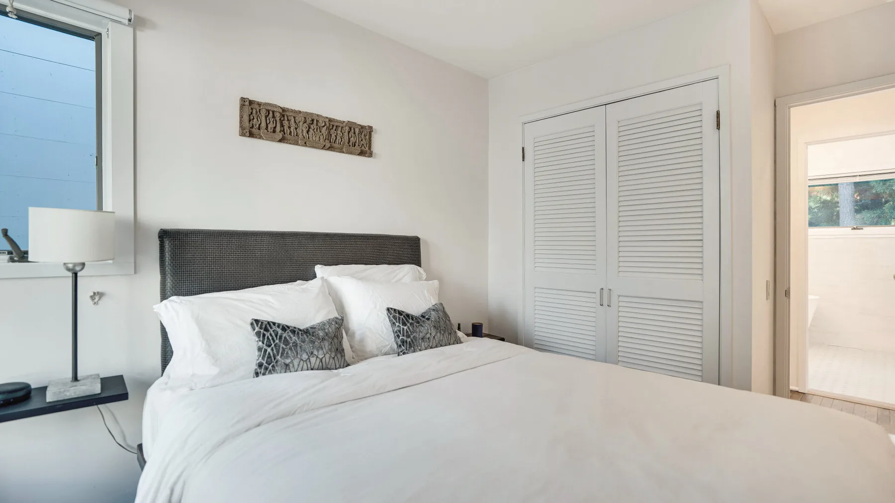 Un dormitorio luminoso con una cama bien hecha y ropa de cama blanca.