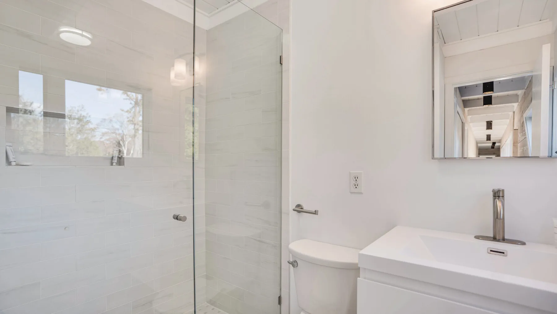 Un baño luminoso con ducha de vidrio, inodoro y tocador.