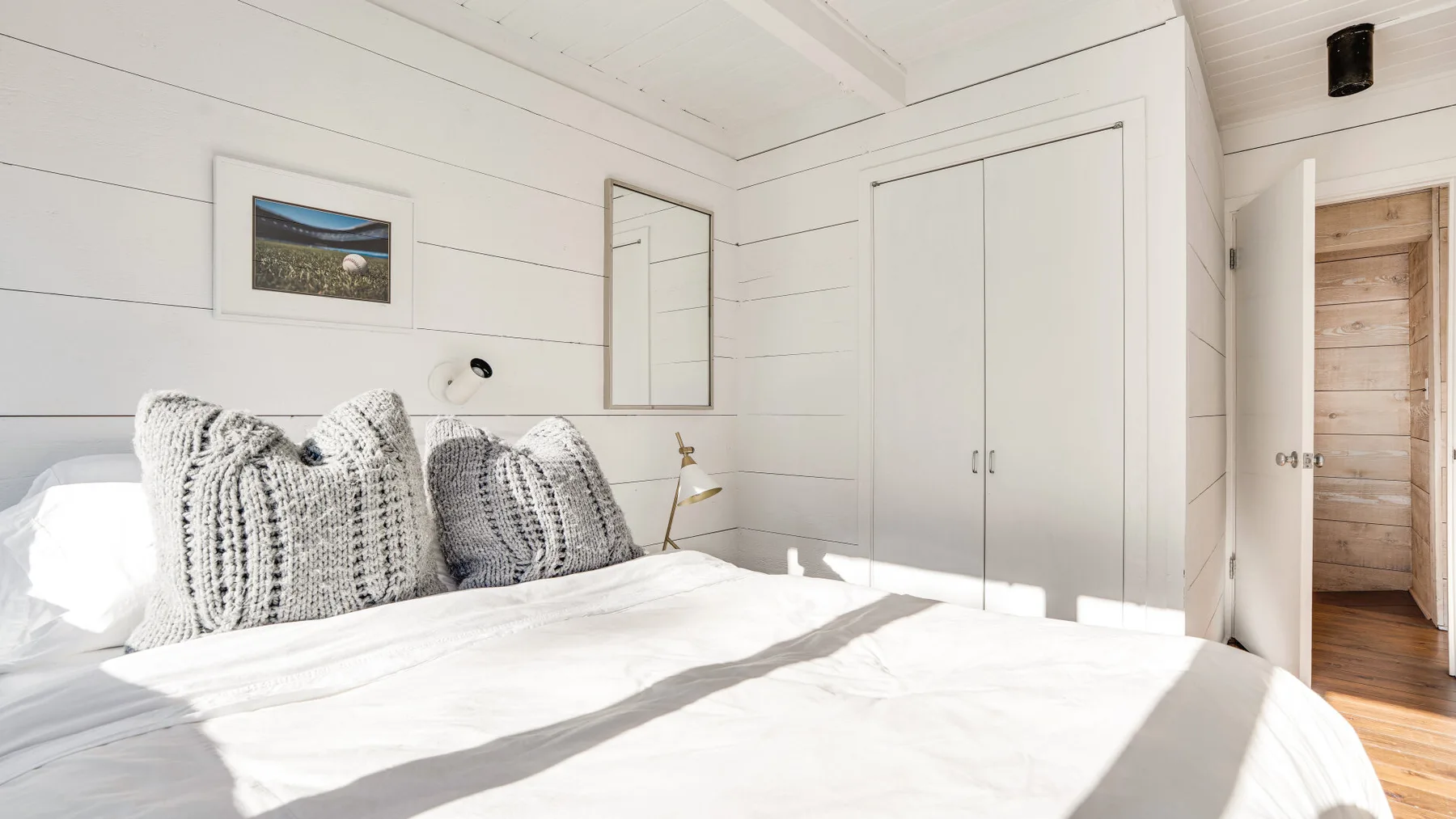 Un dormitorio luminoso con una cama junto a paredes blancas con paneles.