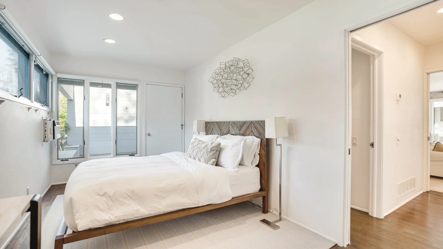 Un dormitorio luminoso con una cama y puertas de vidrio que dan a un balcón.