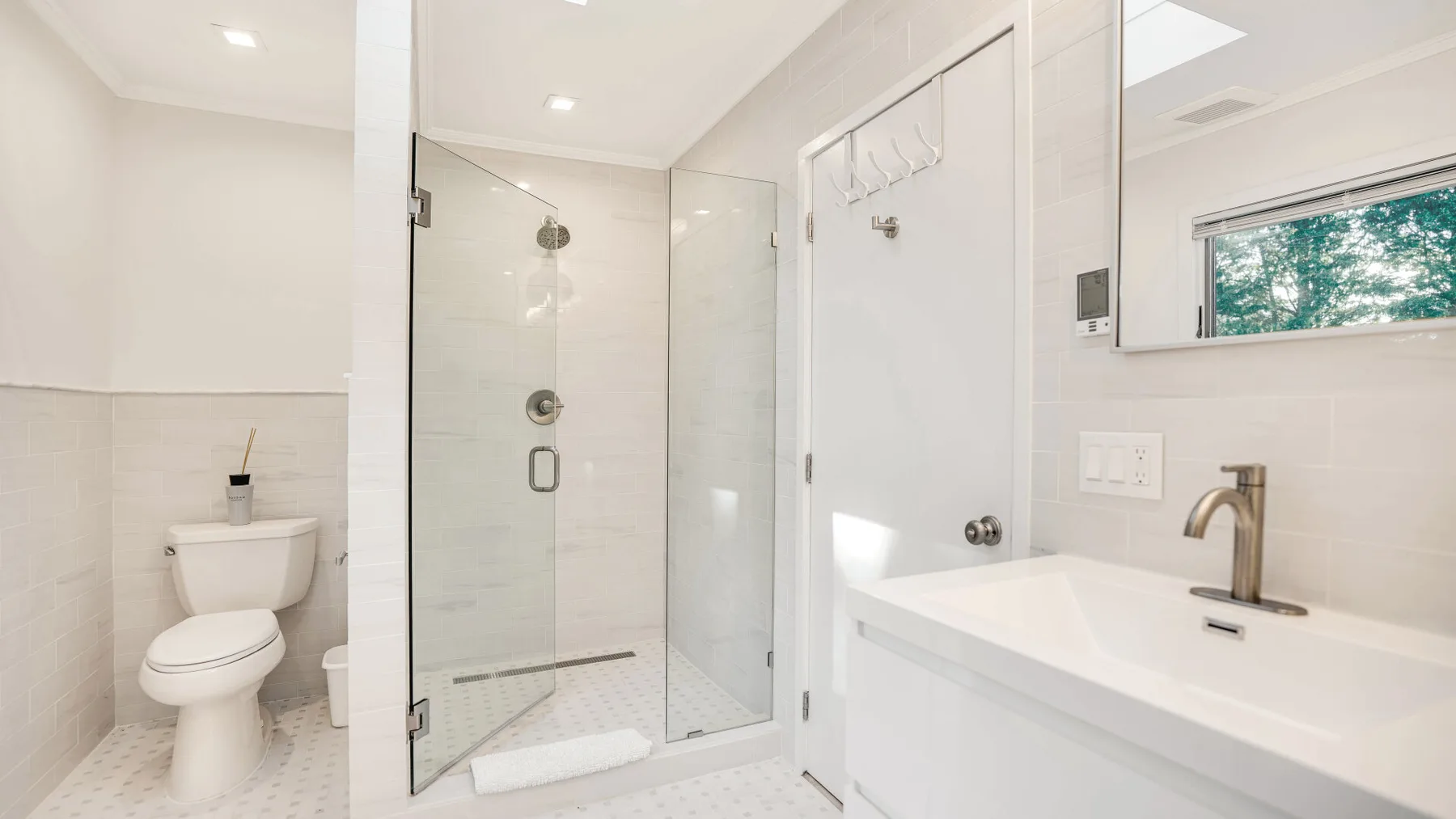 Un baño luminoso con ducha de cristal, inodoro y lavabo.