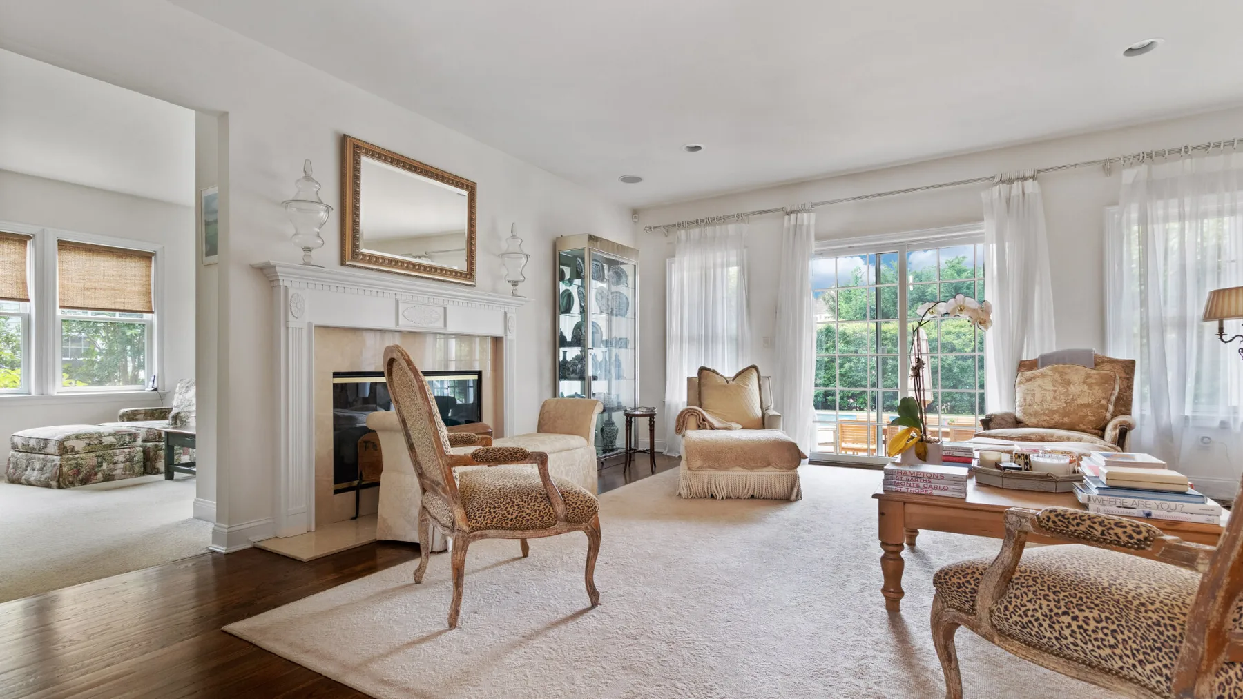 A bright living room with seating, a fireplace, and large windows.