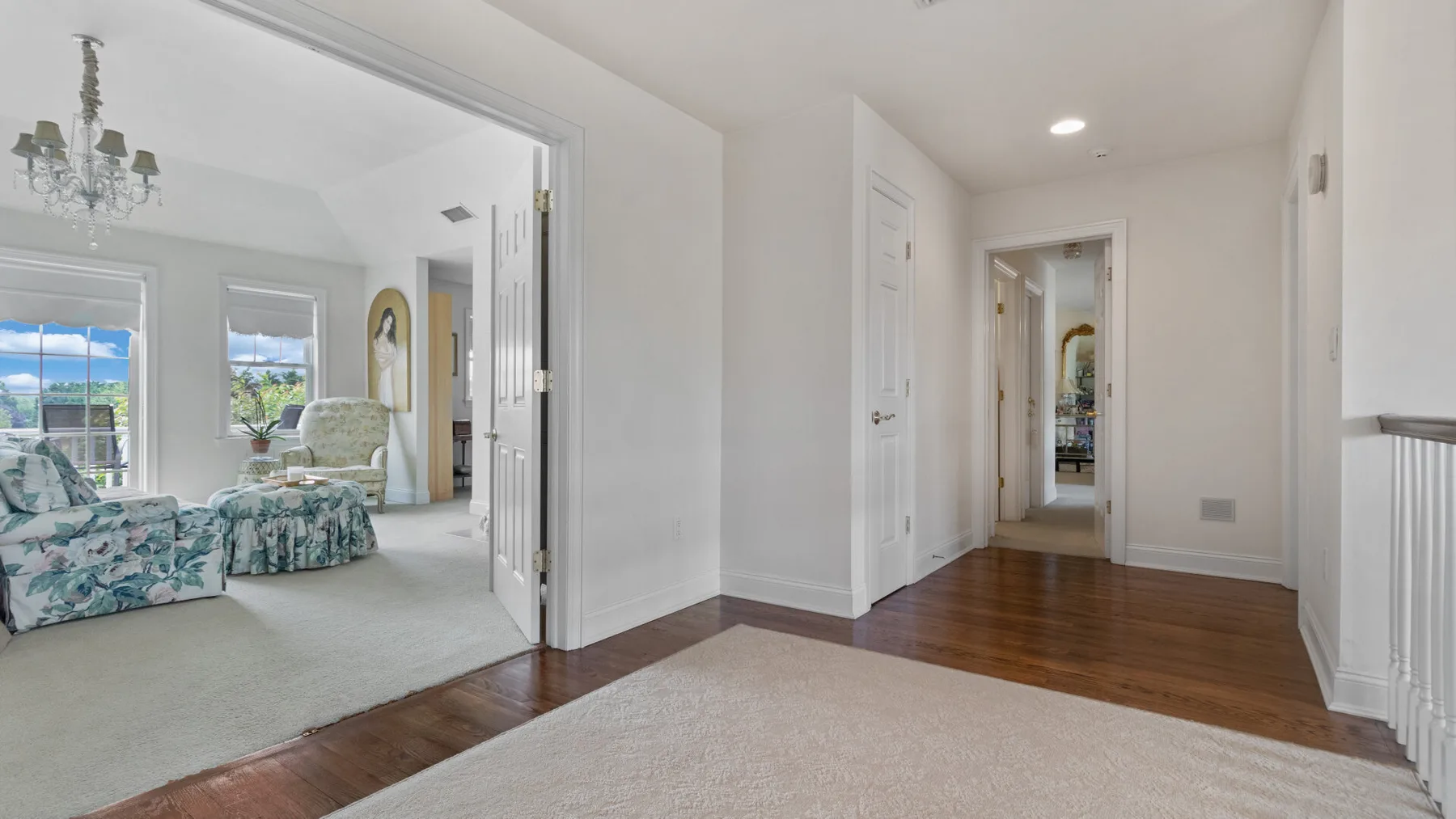 A bright hallway opens into a sitting room with floral seating.