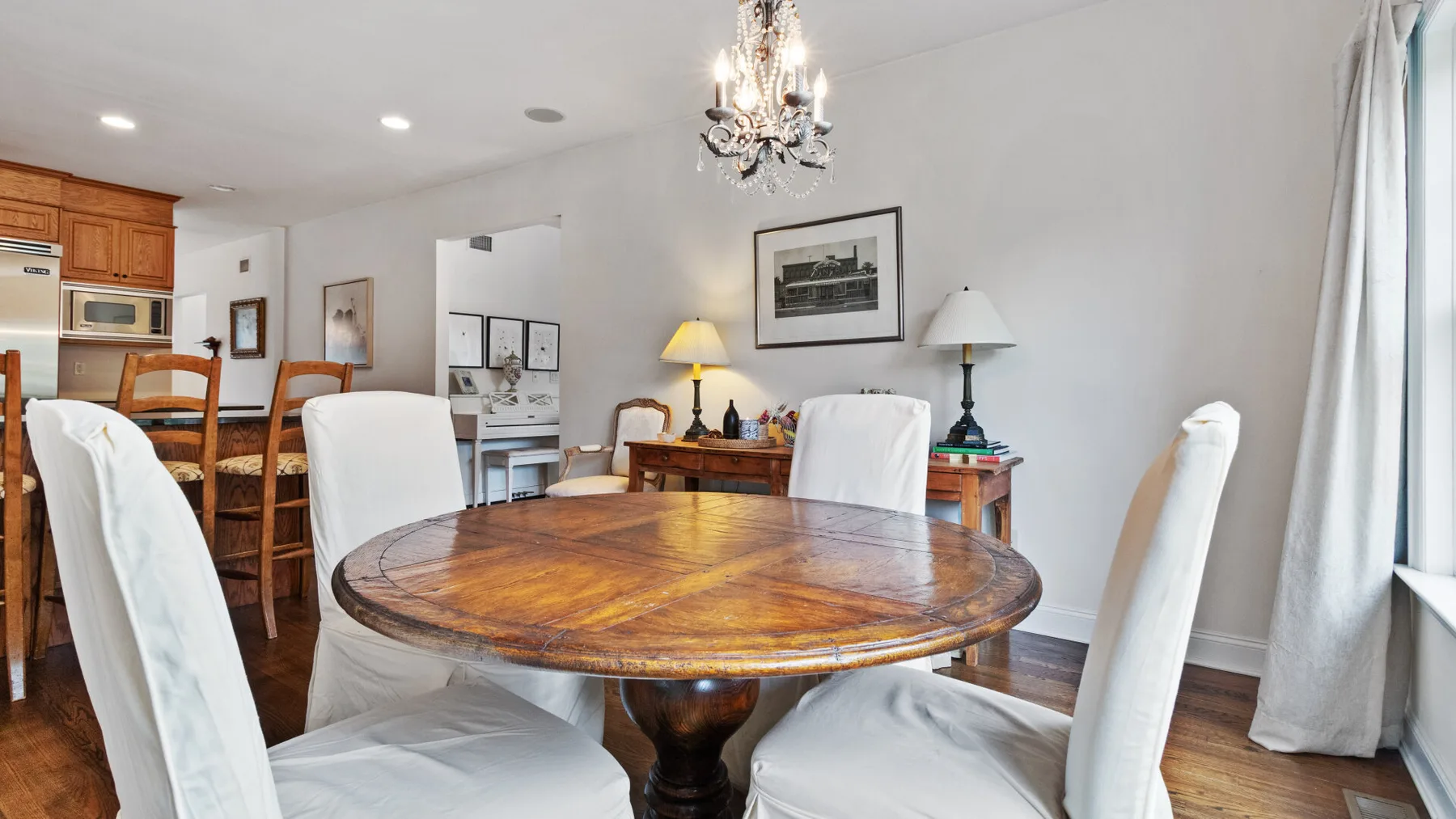 A dining room with a round wooden table and upholstered chairs.