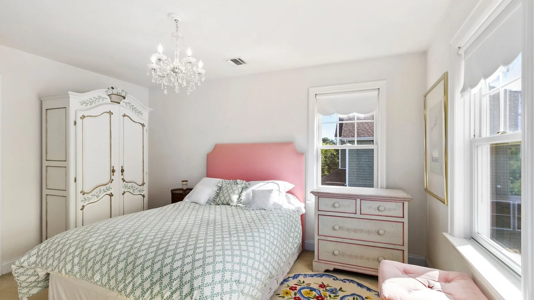 A bright bedroom with a double bed, wardrobe, and windows.