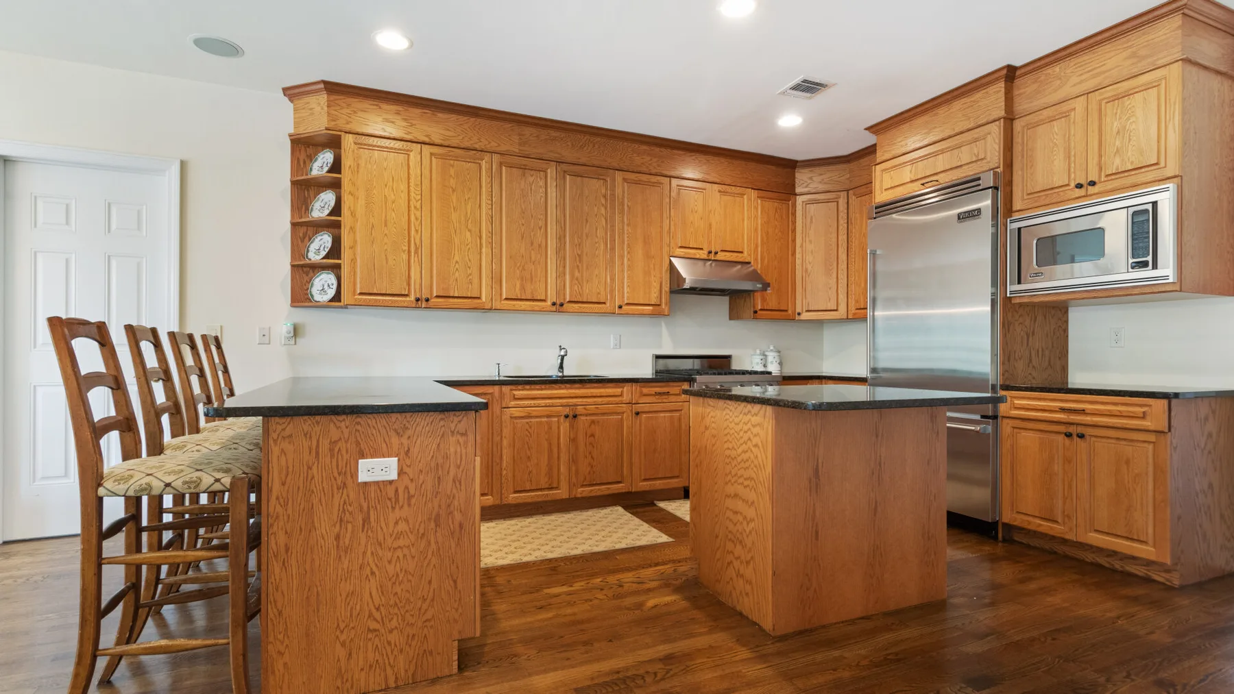 A wood-cabinet kitchen with dark countertops and a central island.