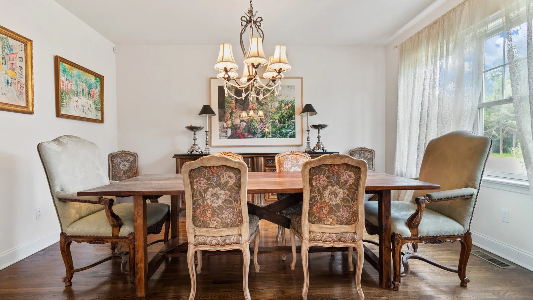 A dining room with a wooden table, upholstered seating, and a chandelier.
