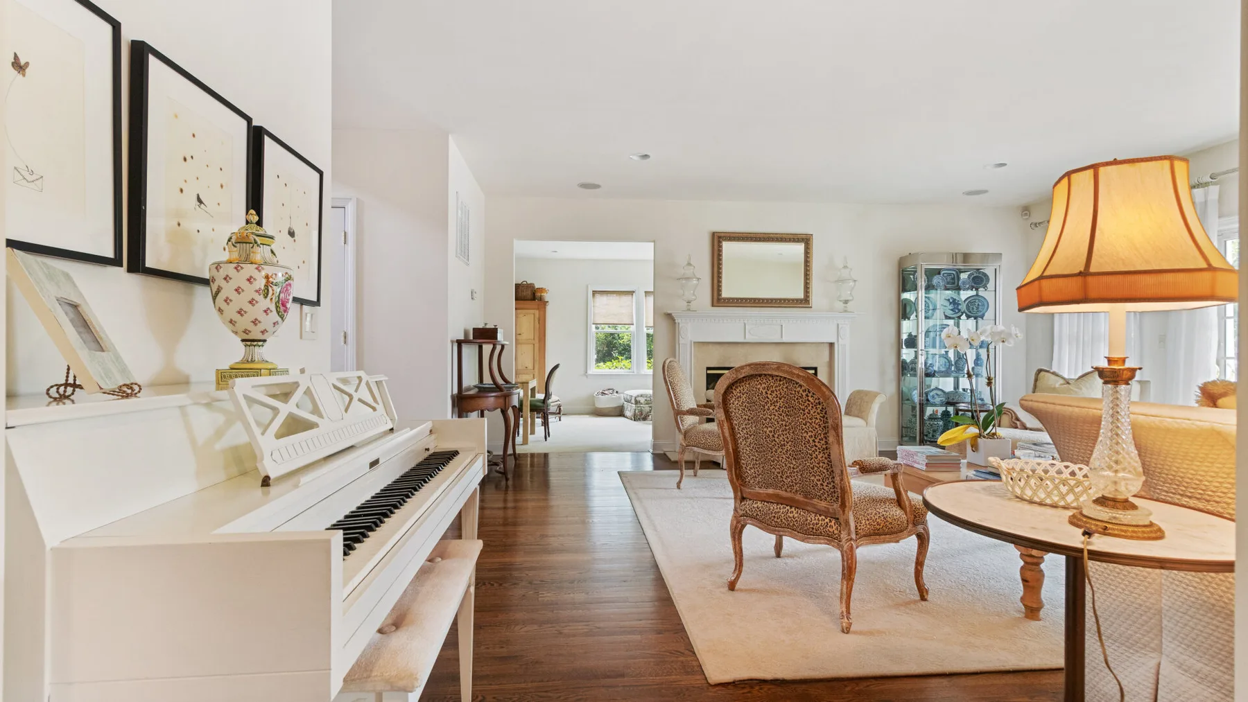 A bright living room with a piano, seating, and a fireplace.