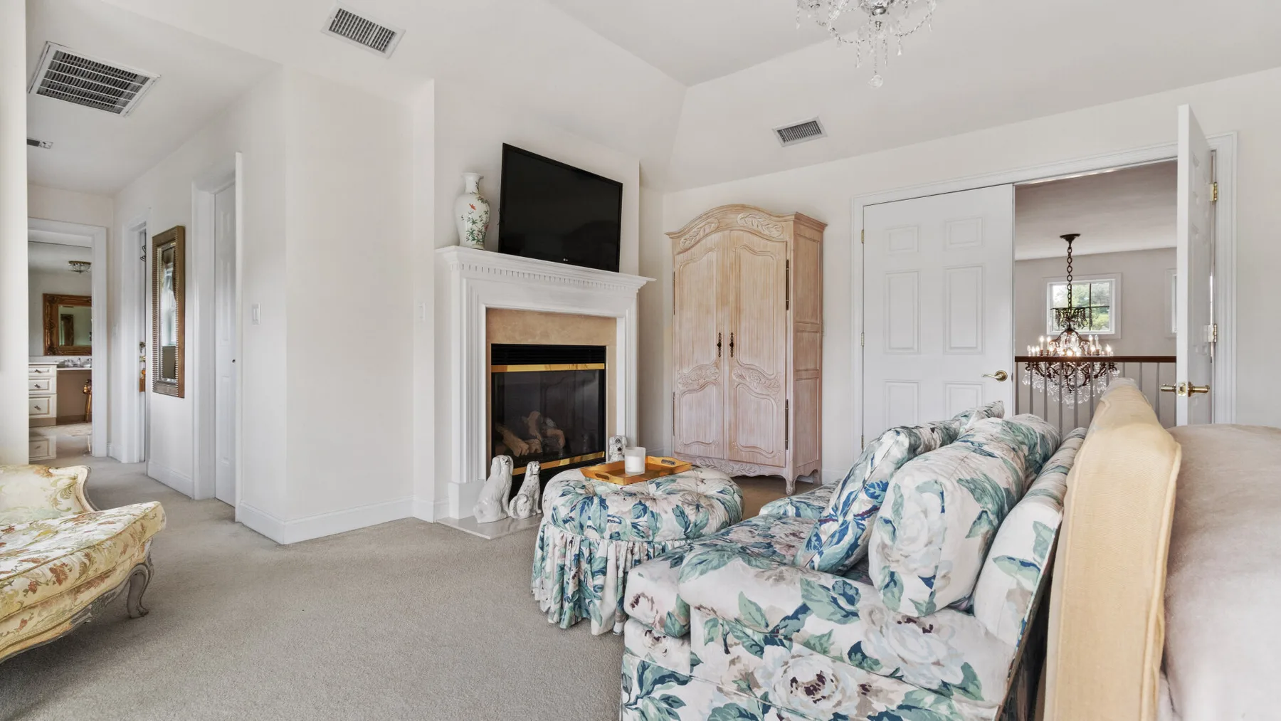A living room with floral seating, a fireplace, and a television.