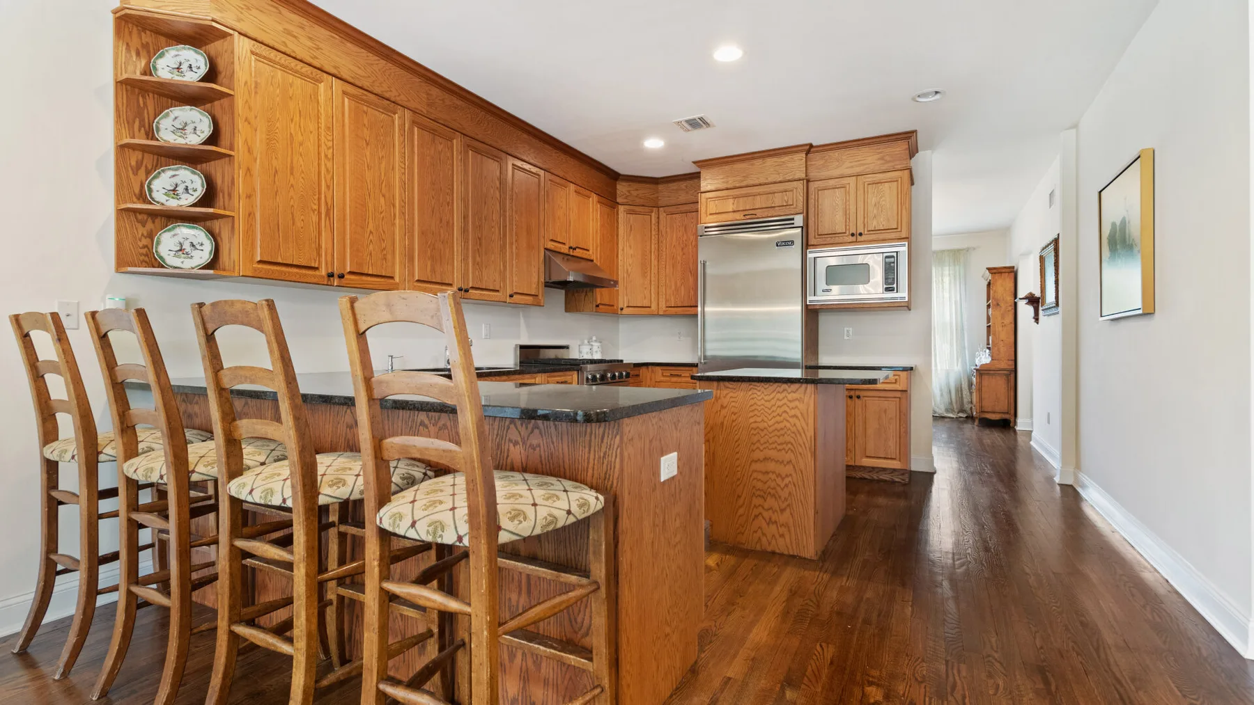 A bright kitchen with wooden cabinets and a central island lined with seating.