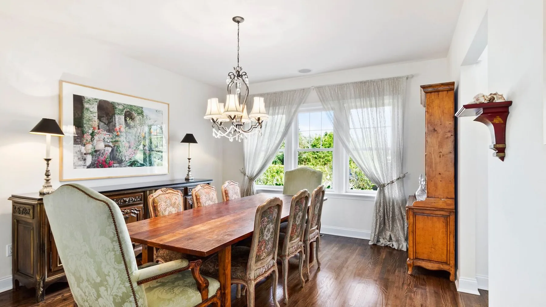 A dining room with a wooden table, chairs, and a chandelier.