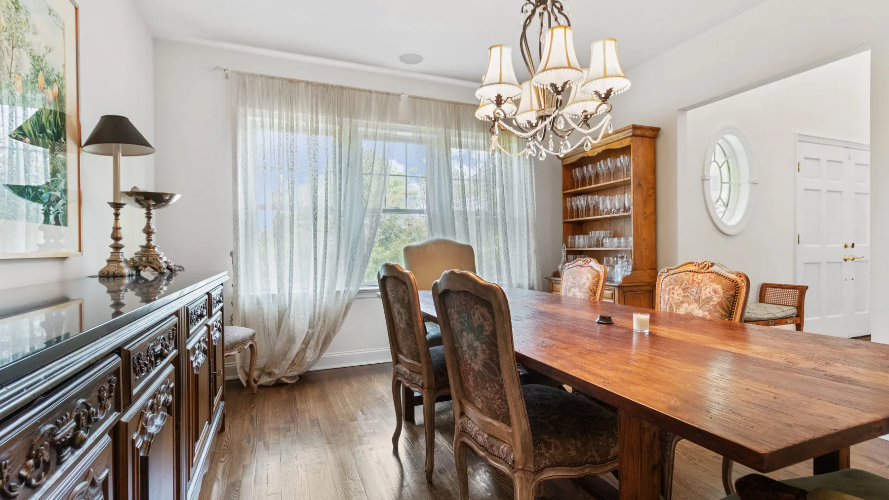 A dining room with a long wooden table, chairs, and a chandelier.