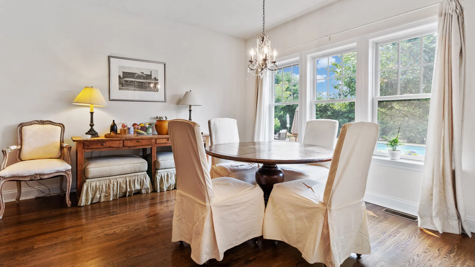 A bright dining room with a round table beside large windows.