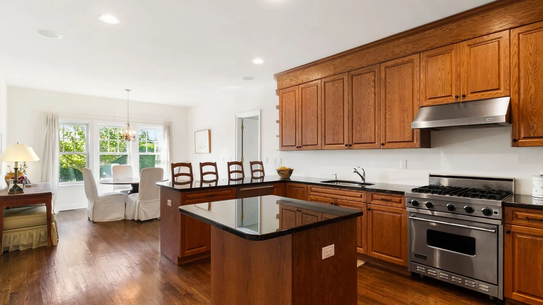 A bright kitchen with wooden cabinets, a central island, and a stainless steel range.