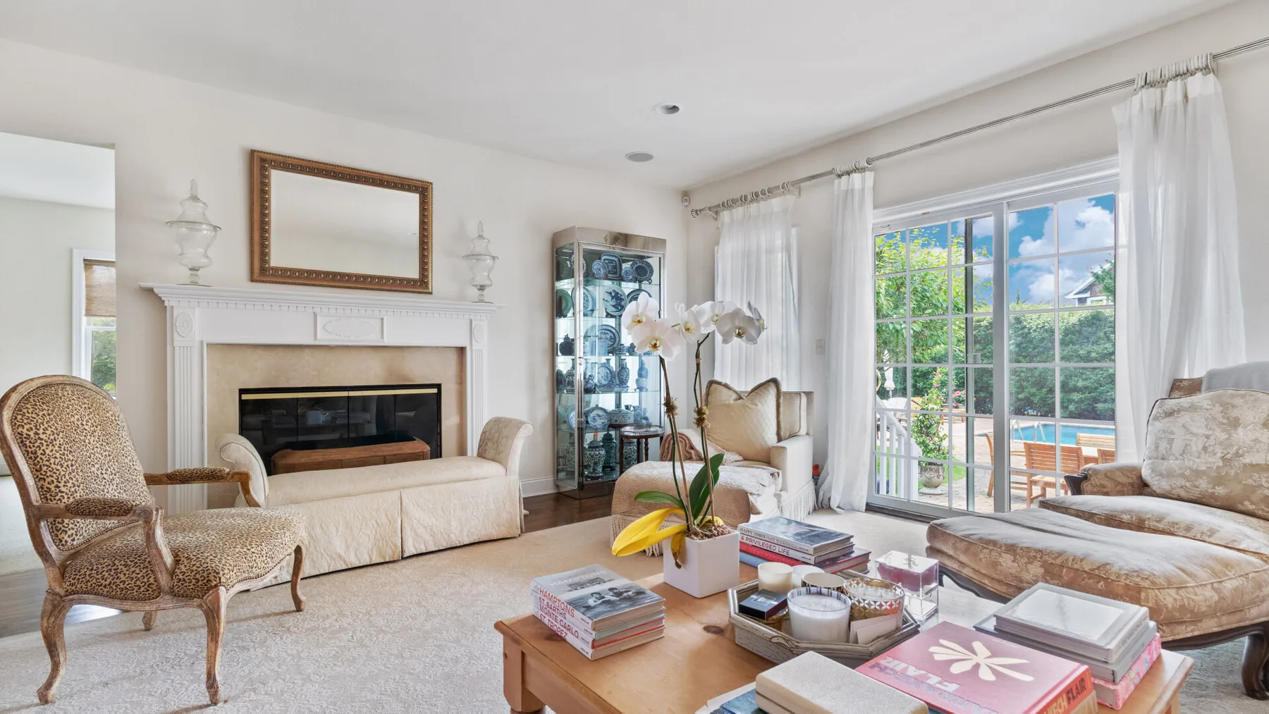 A bright living room with seating, a fireplace, and large windows overlooking a patio.