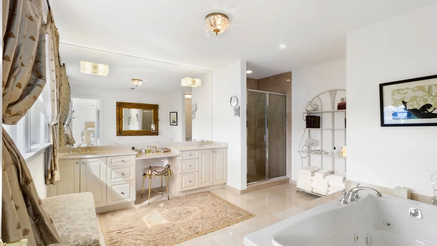 A bright bathroom features a long vanity, a glass shower, and a large soaking tub.