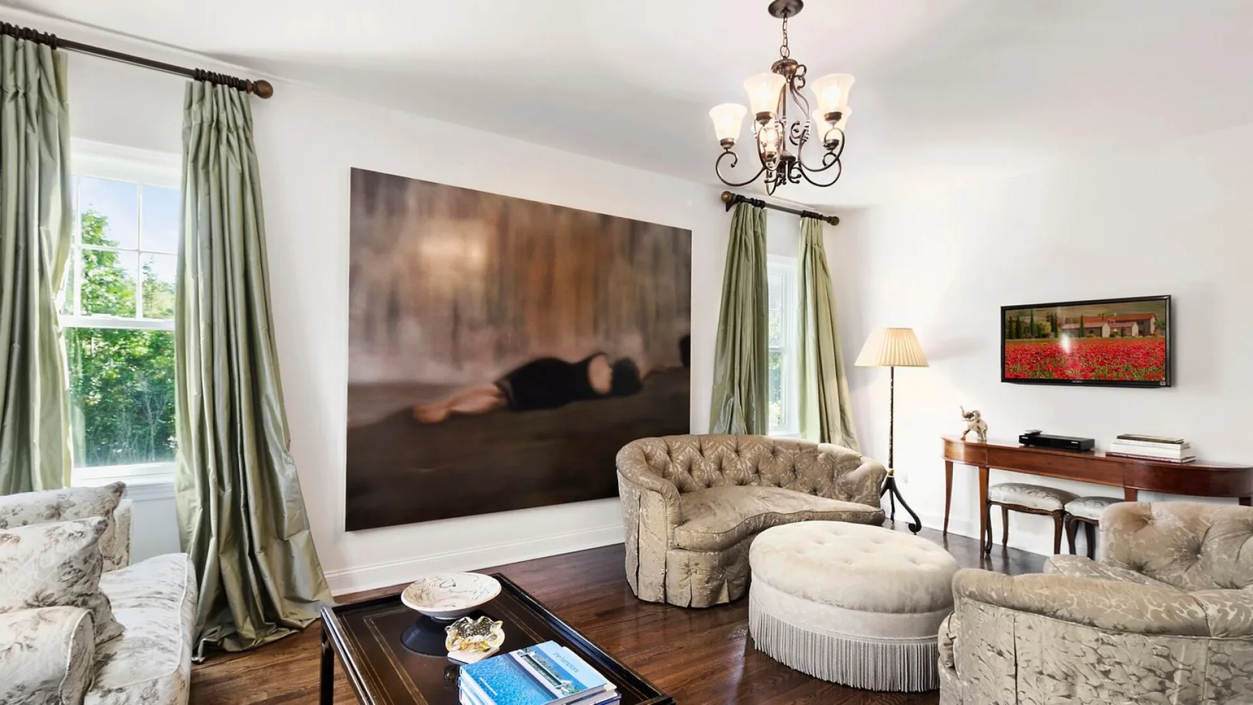 A living room with upholstered seating, green curtains, and a large wall artwork.