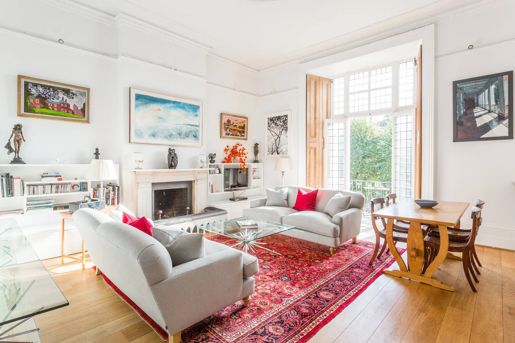 A bright living room with seating around a fireplace and a large patterned rug.