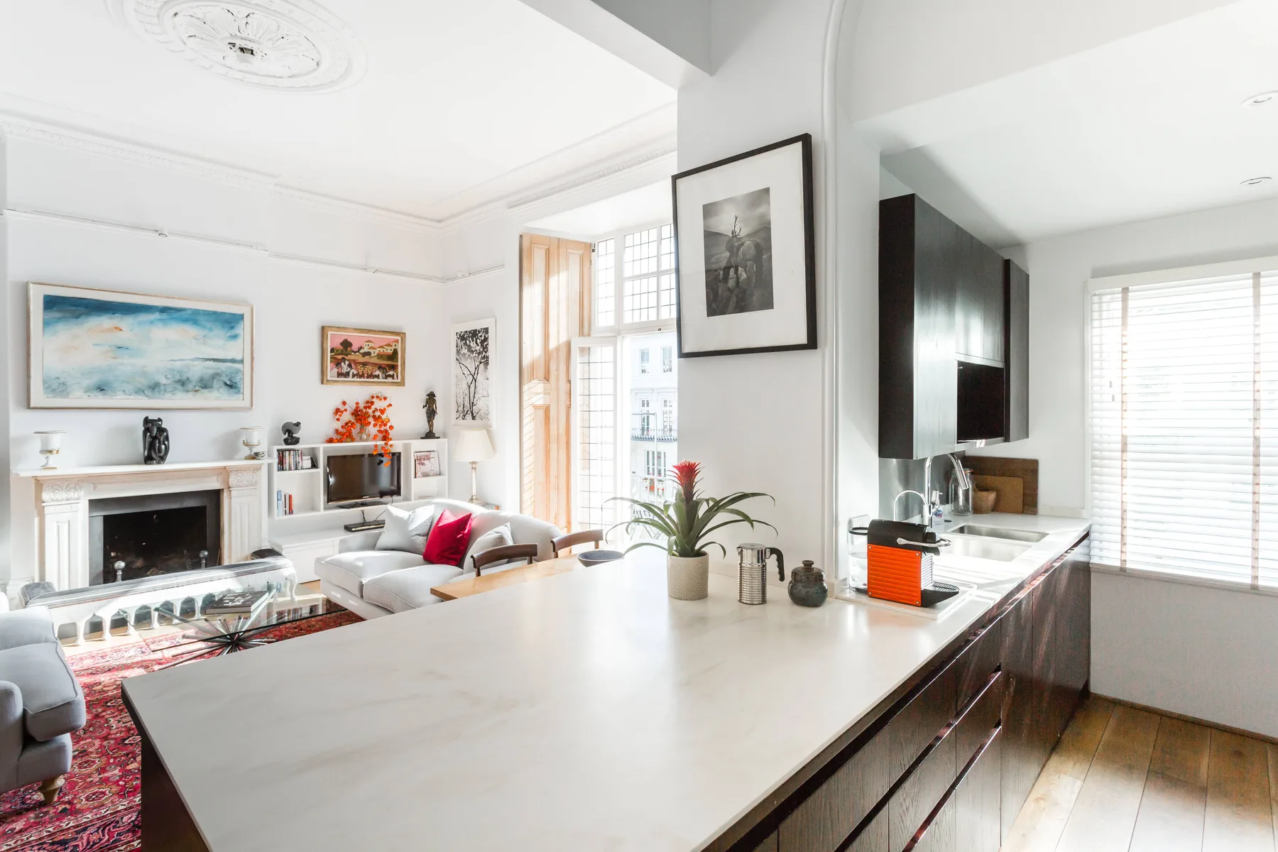 Una luminosa sala de estar y cocina diáfanas, con una gran isla y una zona de asientos.