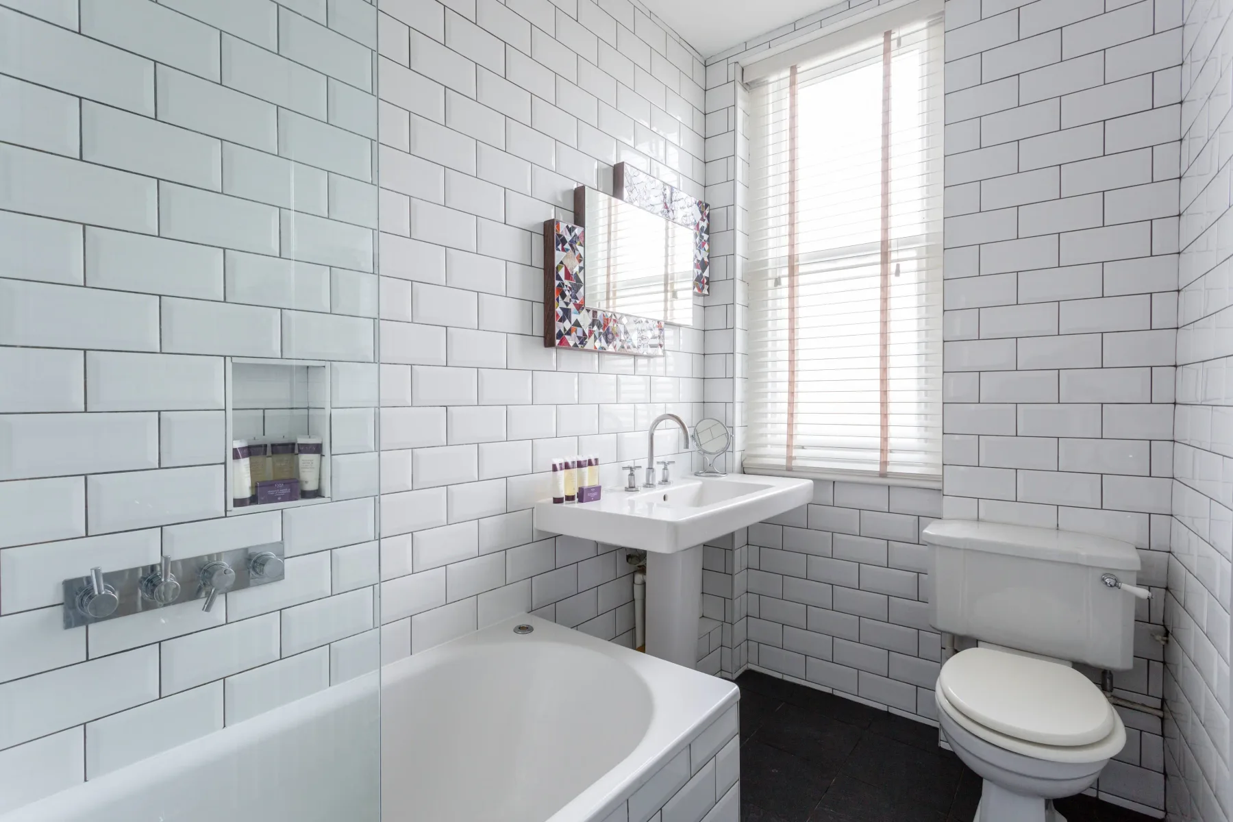 Un baño con azulejos, bañera, lavabo e inodoro.