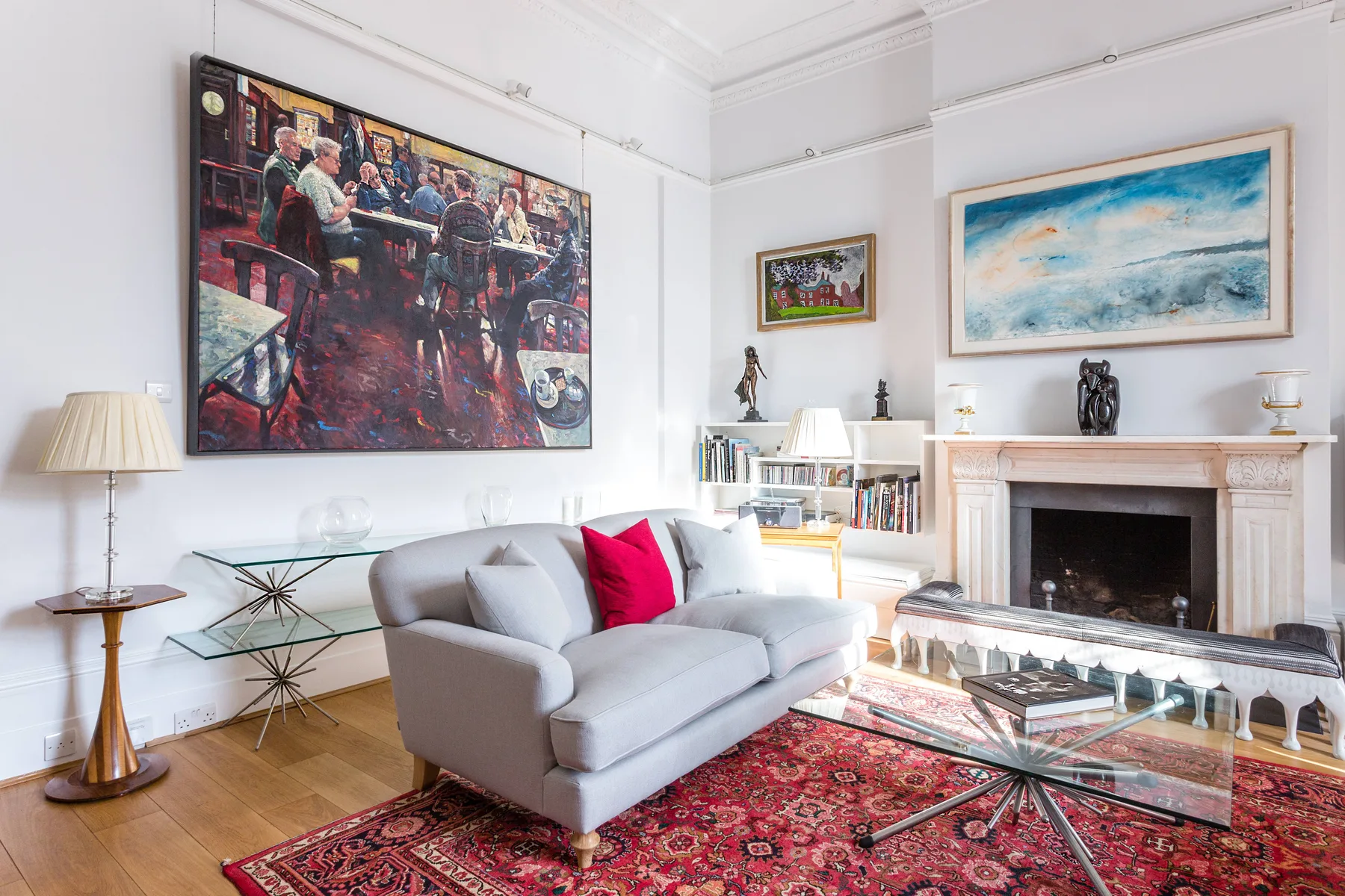 Una sala de estar luminosa con sofá, mesa de centro de vidrio y chimenea.