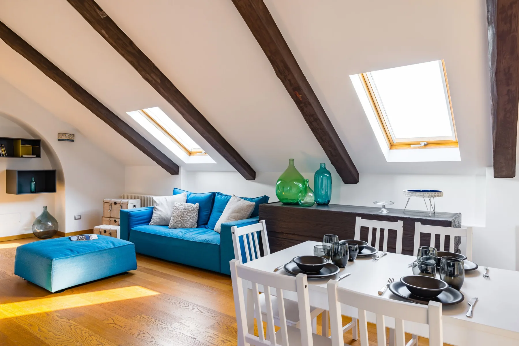 A bright attic living and dining area with blue seating and a white dining table.