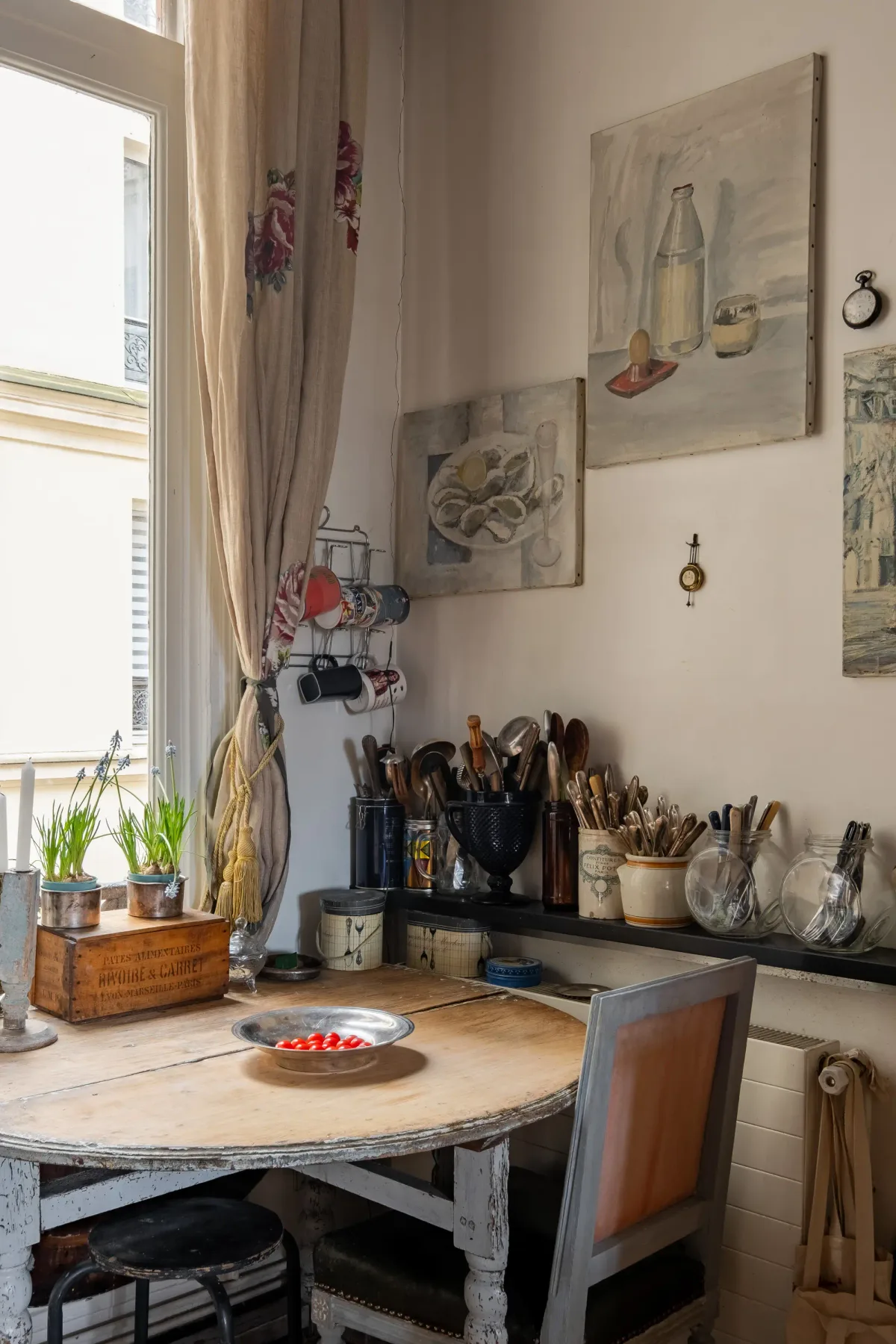 Una luminosa esquina de cocina con una mesa redonda, utensilios y cuadros en las paredes.