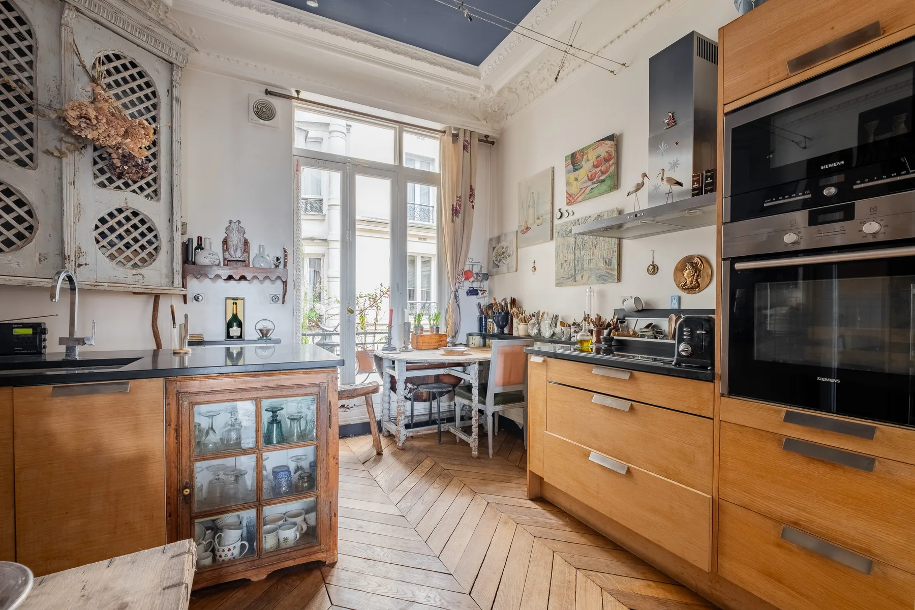 Una cocina luminosa con gabinetes de madera, una vitrina y una pequeña mesa de comedor.