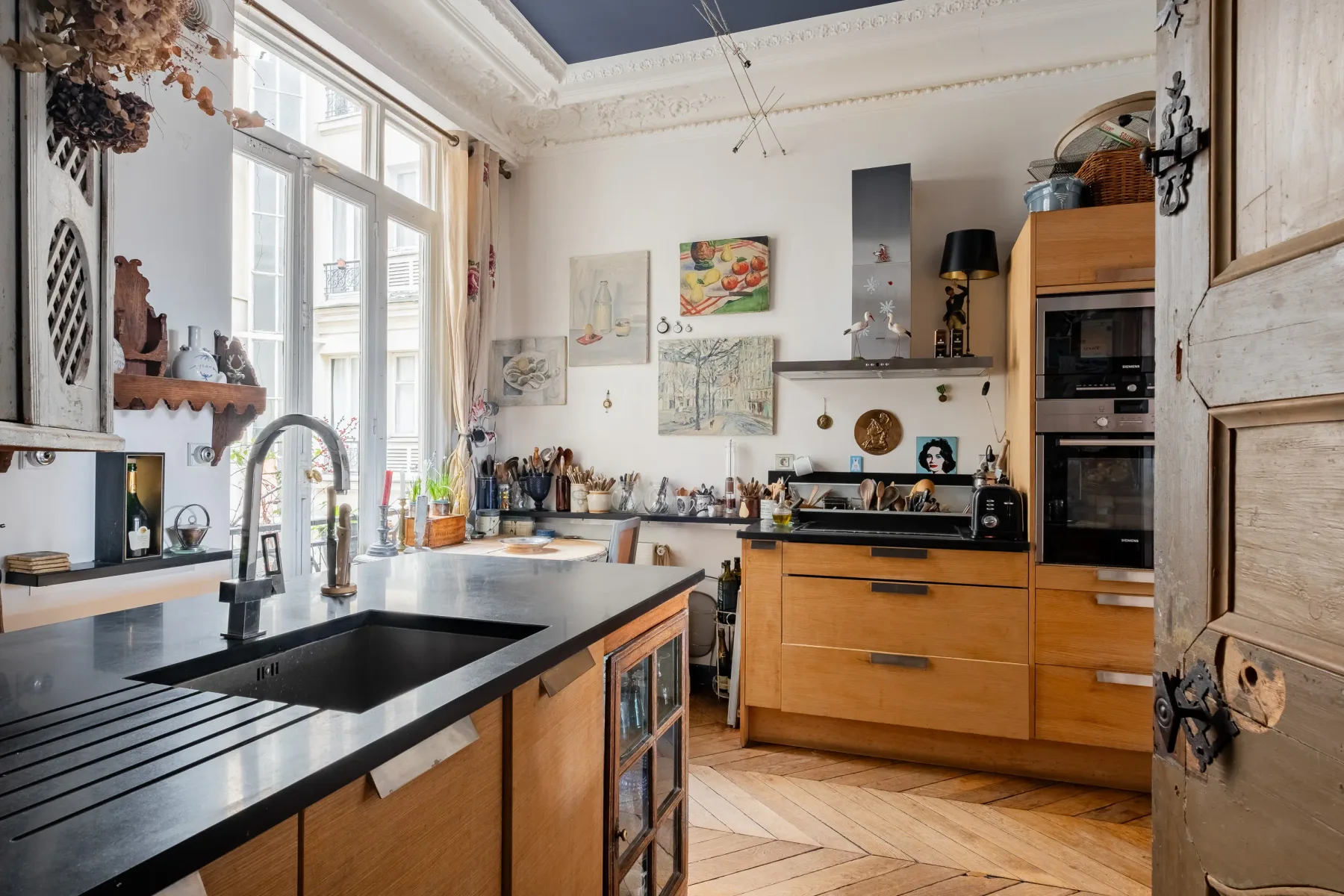 Una cocina luminosa con gabinetes de madera y una gran encimera negra.