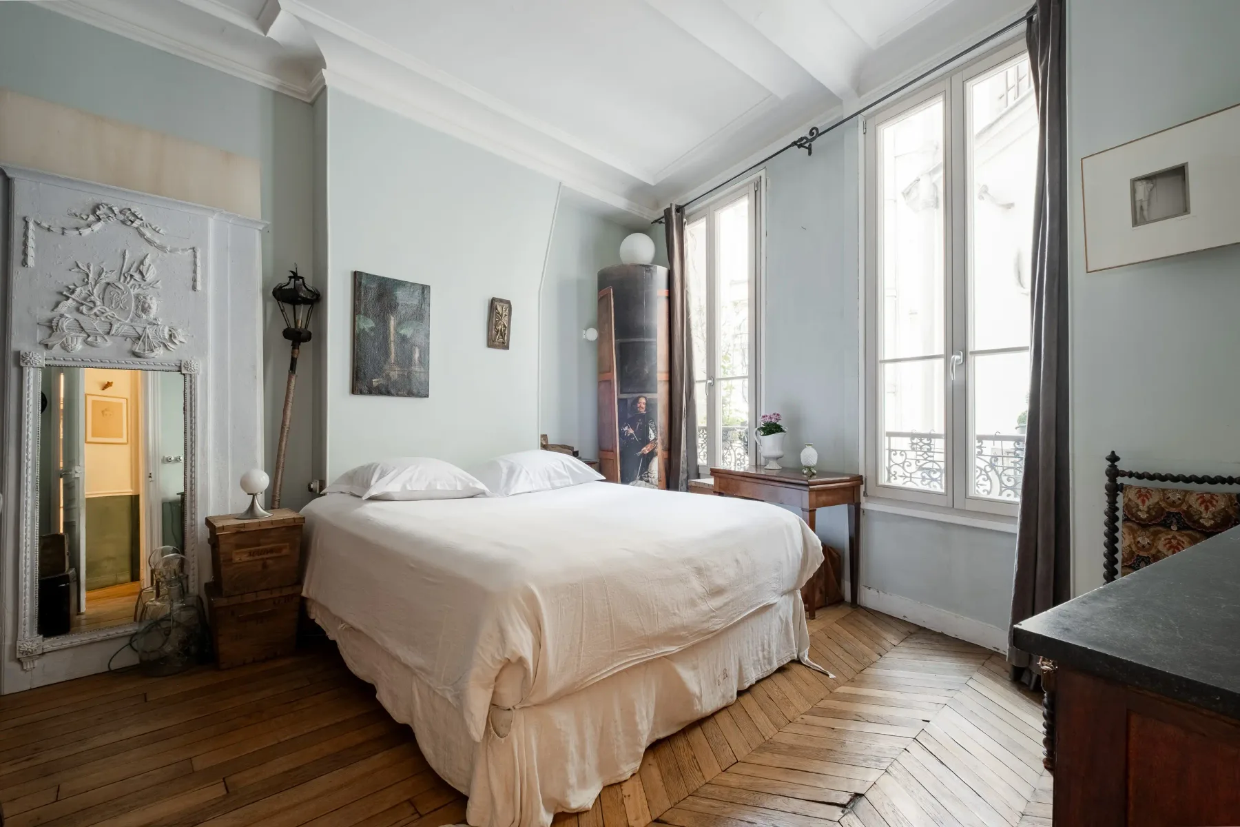 Un dormitorio luminoso con una cama grande junto a ventanas altas.