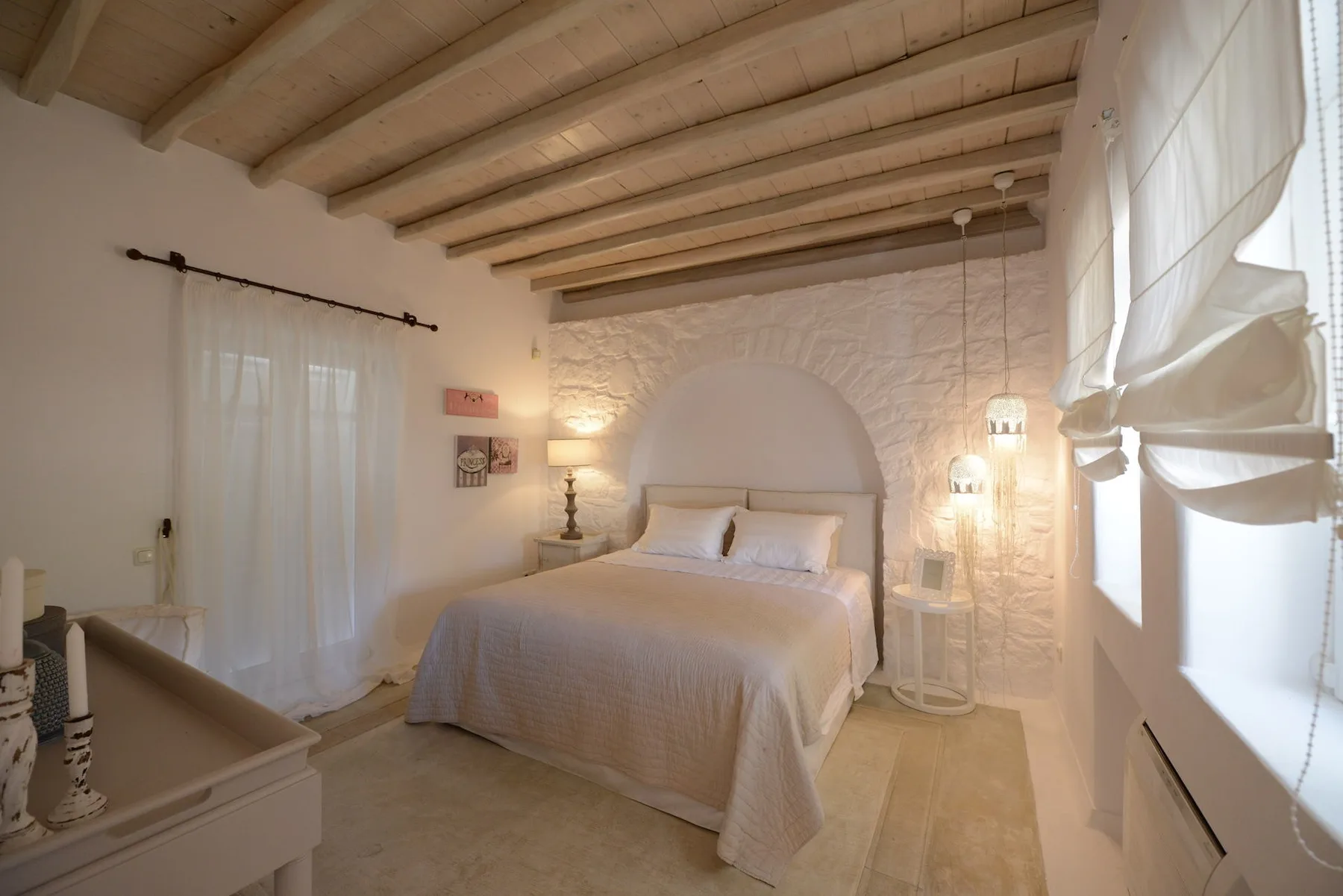 A bedroom with a double bed beneath exposed ceiling beams.
