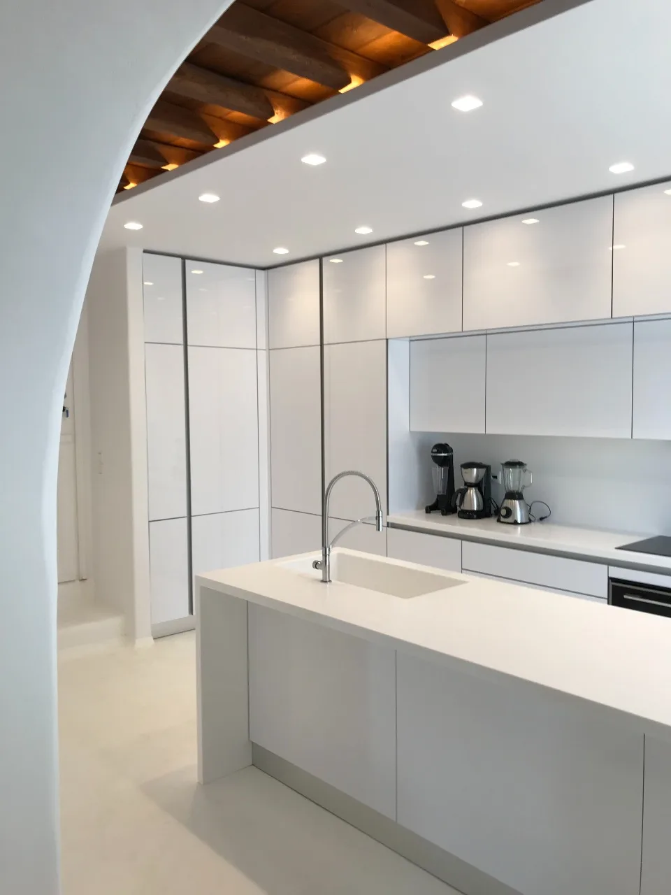 A modern white kitchen with an island and countertop appliances.