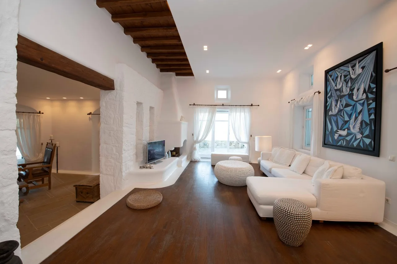 A bright living room with white seating and a large abstract wall artwork.